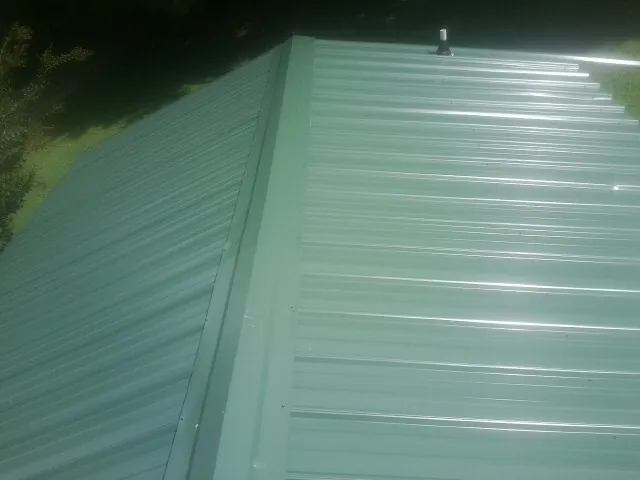 New green metal panels meeting at the ridge of a roof — Flat Roof Repair work by our crew in Camp Verde