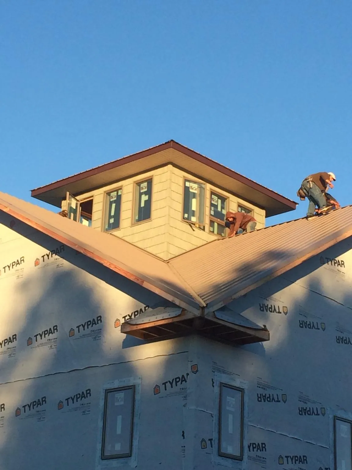 Roofers working around a rooftop cupola on a new metal roof at sunset — Roof Waterproofing in Camp Verde by Roofing Brothers